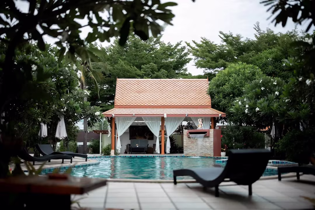 Luxury Thai pool pavilion with traditional roof surrounded by tropical gardens