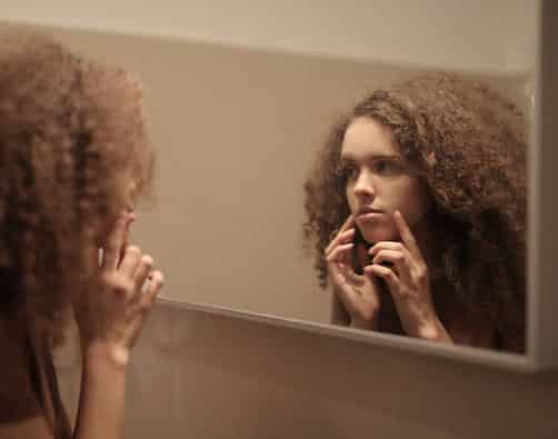 female-looking-at-the-mirror-touching-her-face