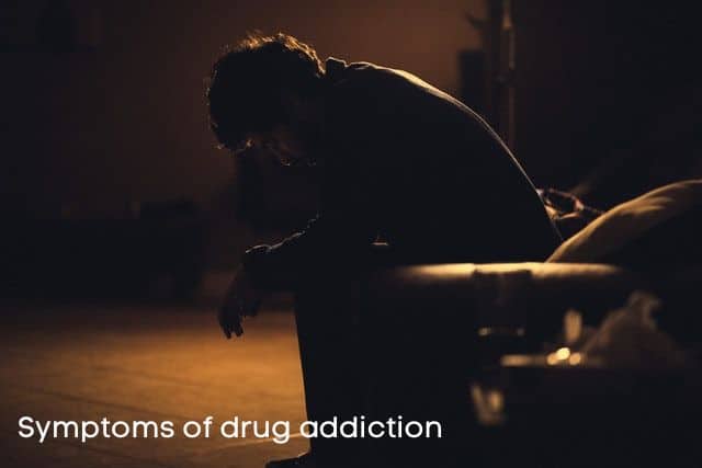 symptoms-of-drug-addiction-sign-and-a-man-sitting-in-the-dark