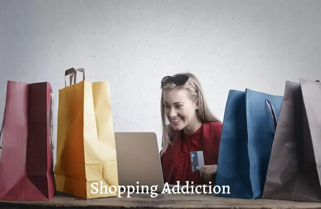 woman holding credit card in front of a laptop with shopping bags on both sides