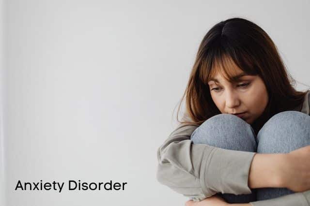 woman hugging her knees and Anxiety Disorder sign