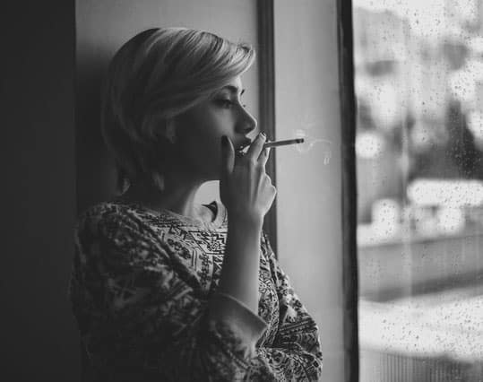woman-smoking-cigarette-near-window