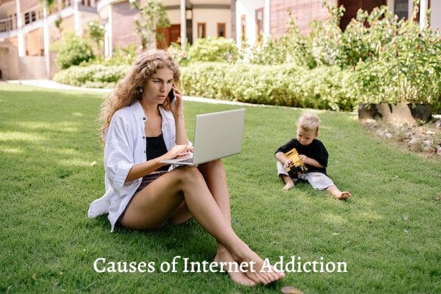 woman-sitting-on-a-grass-talking-to-a-phone-and-working-on-a-laptop-with-a-baby-playing-on-the-side
