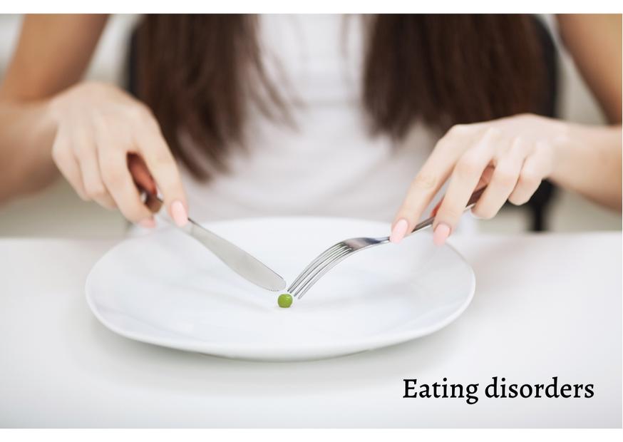 Female with fork and a knife cutting a pea on a plate