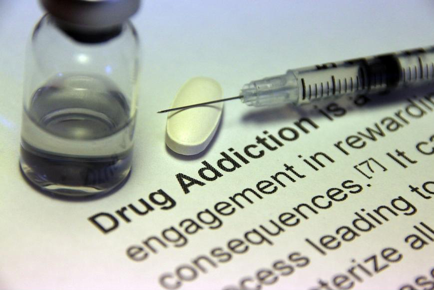 Syringe-a-medicine-bottle-and-a-pill-next-to-a-drug-addiction-sign.